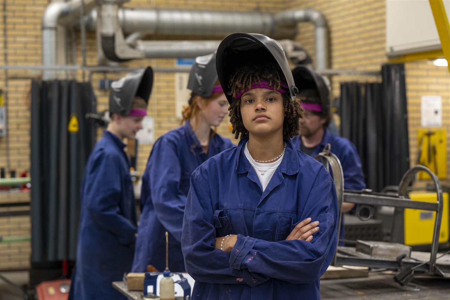 Jonge student in blauw overall met beschermingshelm op